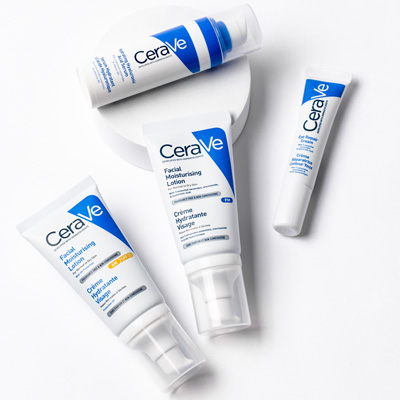 Bright white image with 4 CeraVe products laid down organically on a white surface, with 2 resting on a circular podium
